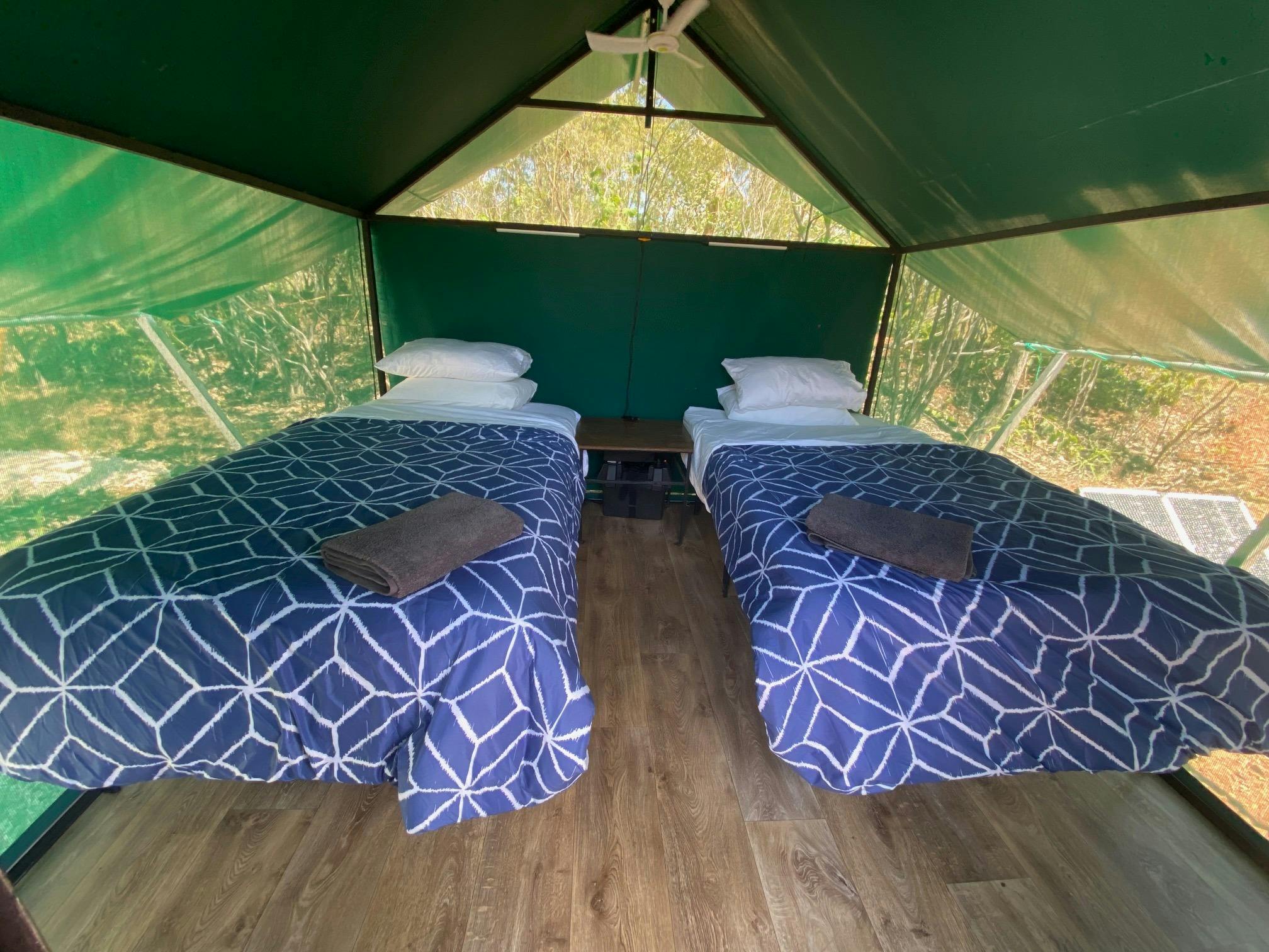 2 King Single Beds with pillows are pictured in a tent with a fan above