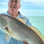 A man holding a fish on a Darwin Red Devil Charter.
