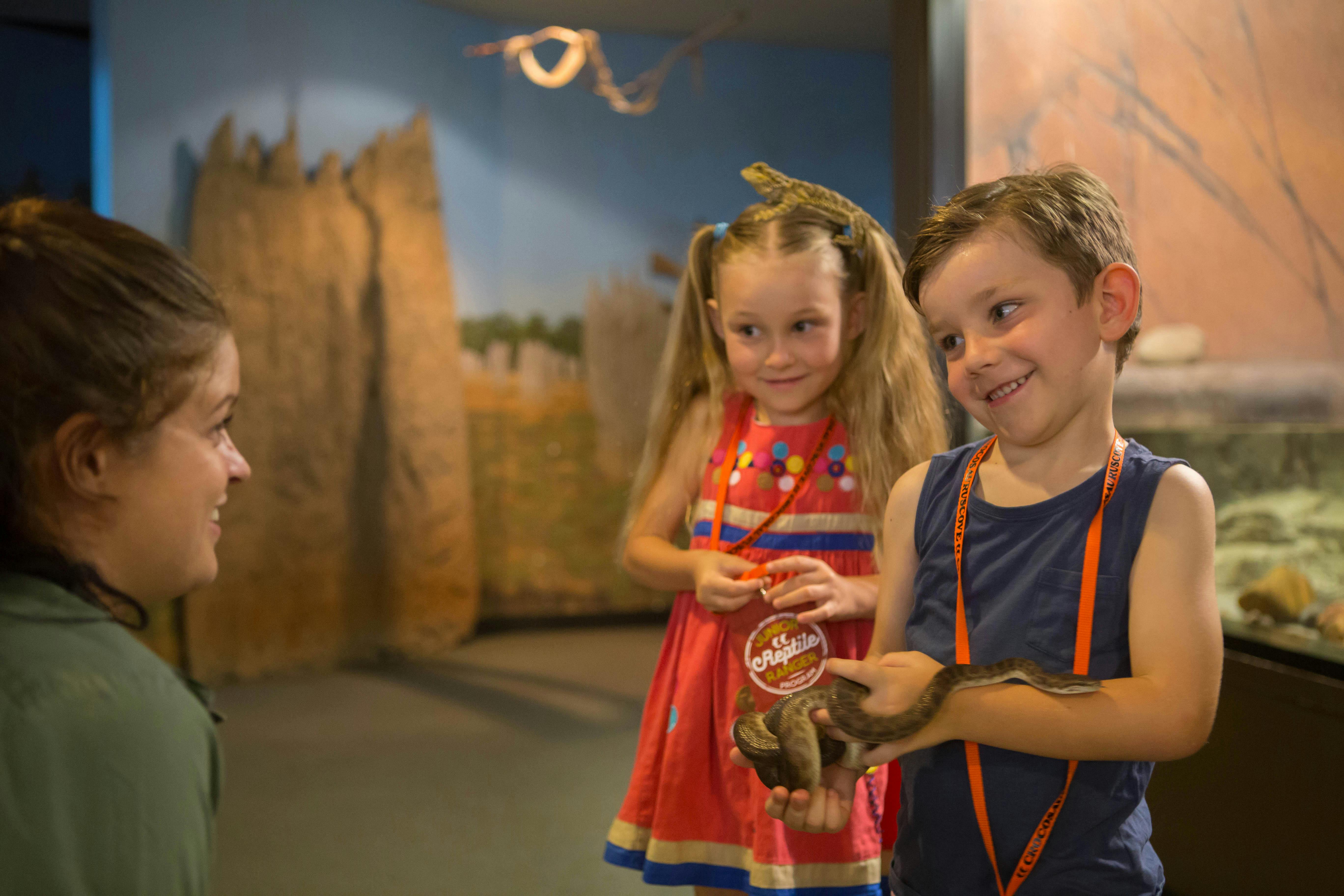 two children meeting snakes and lizards during the Junior Reptile Rangers program at Croc Cove