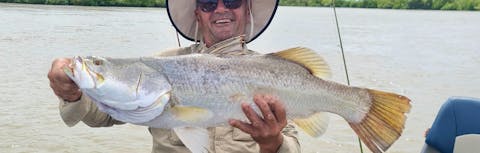 A man in a fishing boat holding the fish he had caught.