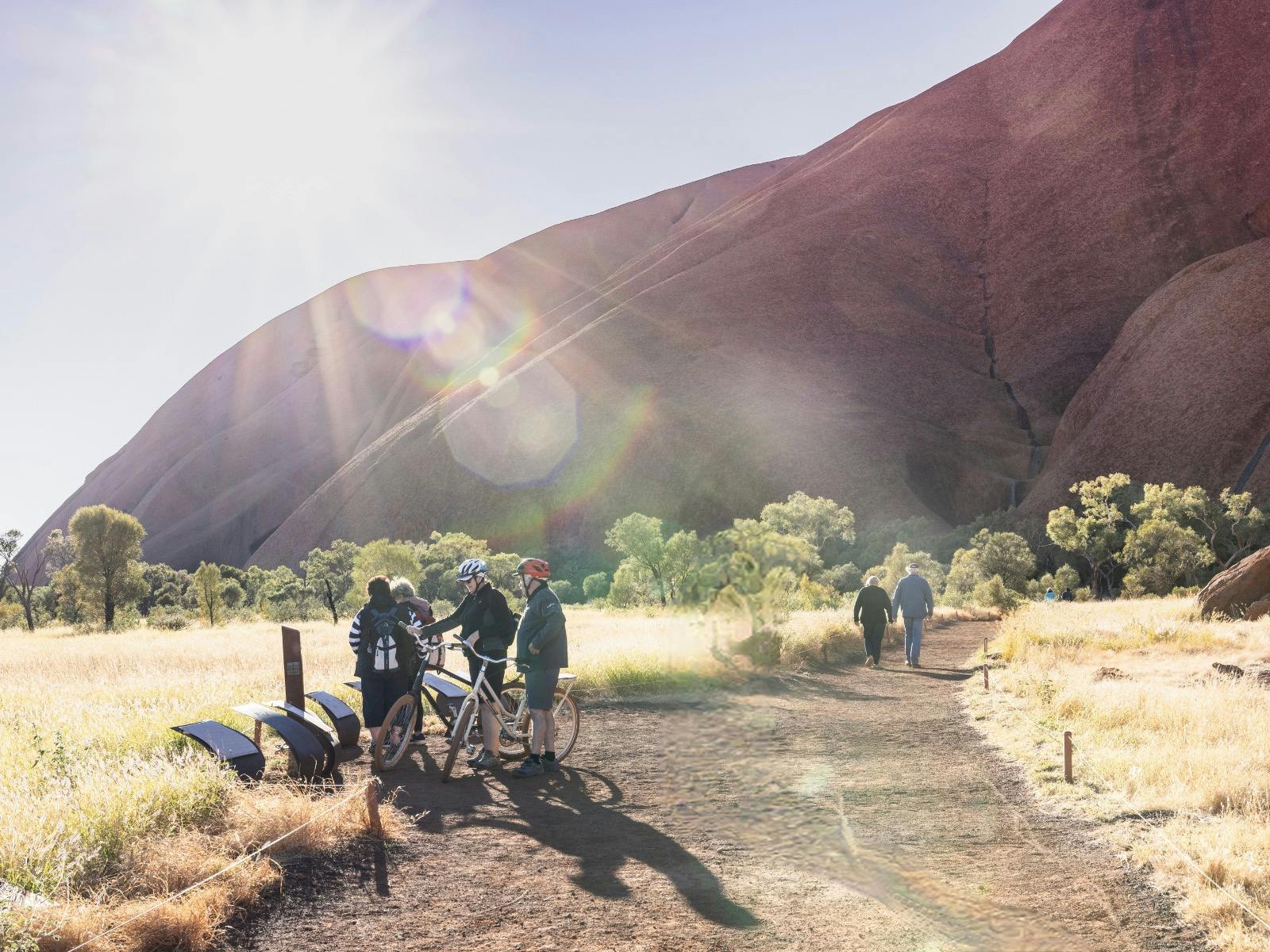 group standing with bikes reading signs at the base of Uluru