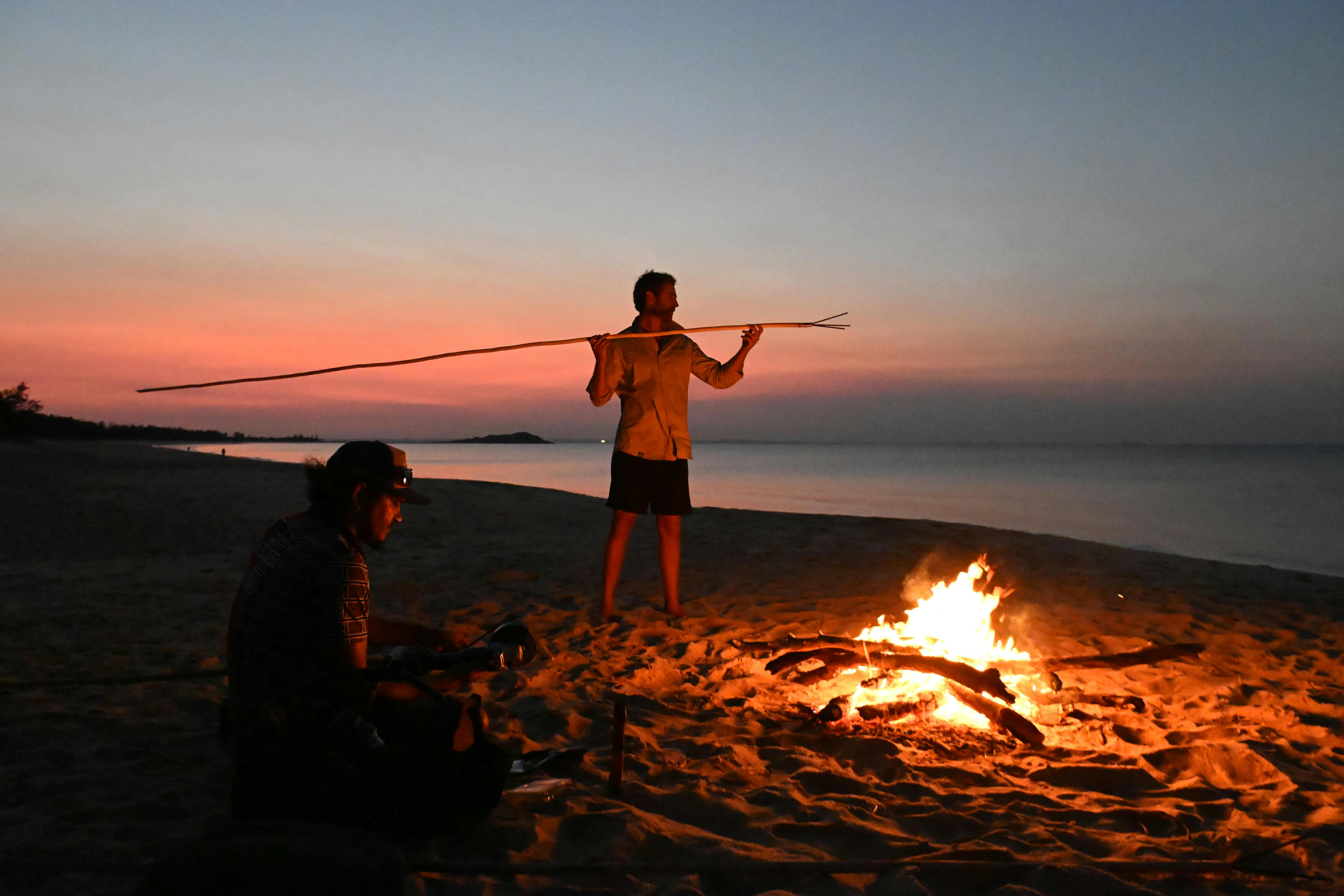 Visitors crafting spears over the fire at Galaru (East Woody Beach) as the sun sets