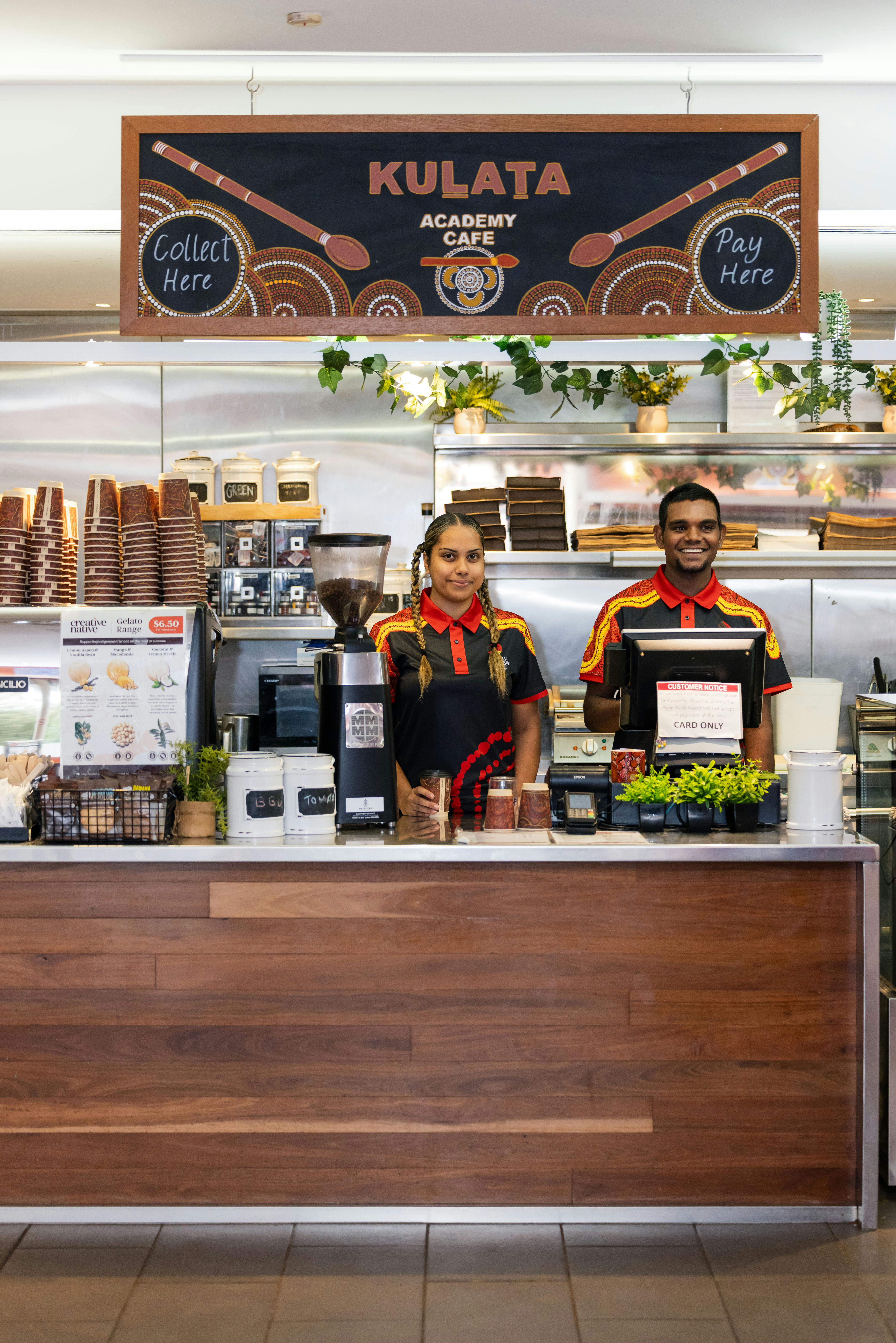 Smiling and welcoming Cafe Staff standing behind coffee machine