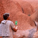 A man stands at Uluru and is  mesmerised by the audio guide he is listening to.