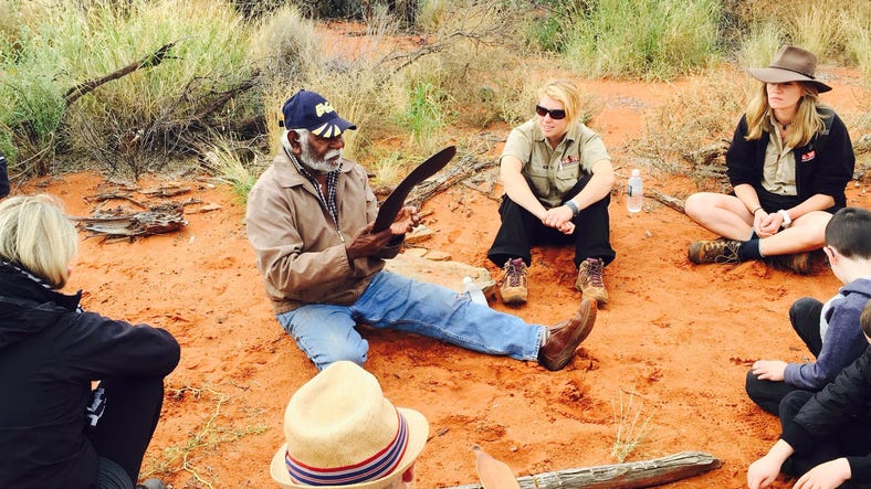 An Anangu host showing a tour group how to make tools at the Cave Hill tour