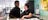 A_waitress_is_talking_and_smiling_with_a_waitor_pointing_at_some_document_with_lanyard_on_the_counter_in_a_shop.jpg