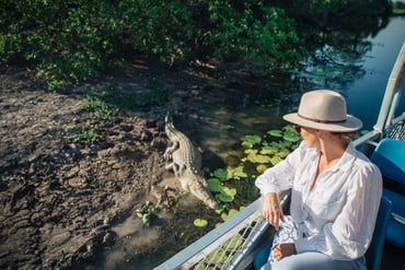 A woman looking over the edge of a cruise boat at a crocodile in Yellow Water Billabong in Kakadu