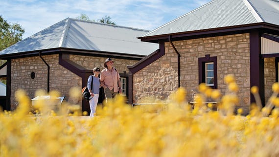 Viewing the historic buildings at the Telegraph Station Historic Reserve with wildflowers in the foreground