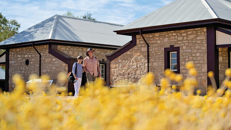 Viewing the historic buildings at the Telegraph Station Historic Reserve with wildflowers in the foreground