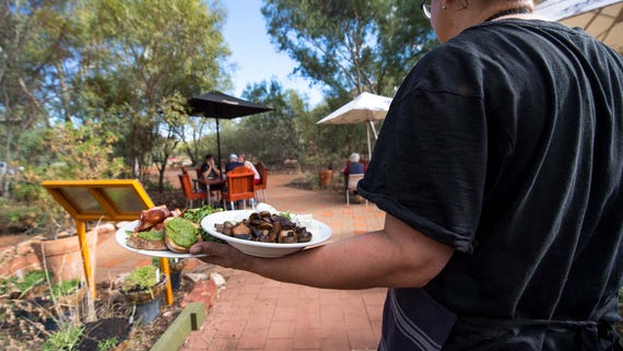 Lady serving breakfast to guests at the Olive Pink gardens