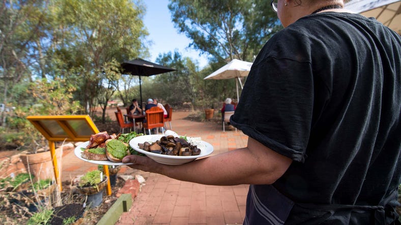 Lady serving breakfast to guests at the Olive Pink gardens