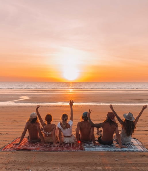 Friends sitting together watching sunset on the beach