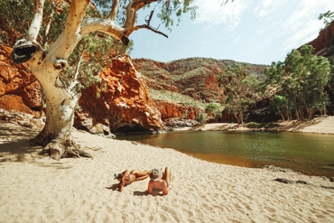 Two friends sunbathing waterside at the waterhole in Ormiston Gorge near Alice Springs