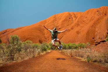 man jumping in front of Uluru
