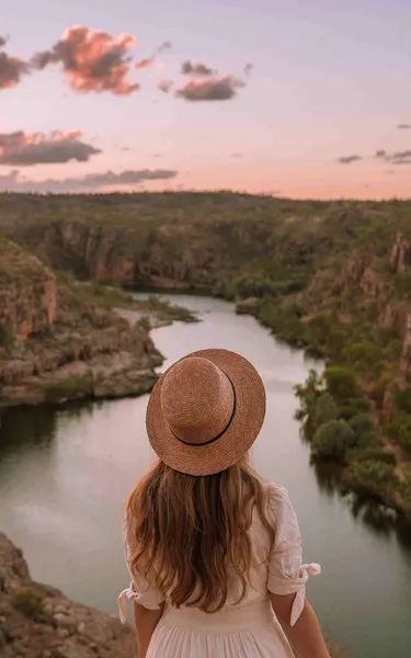 Girl standing on the edge of a weaving escarpment in Katherine Gorge at sunset