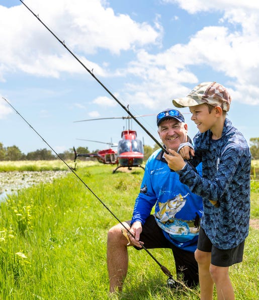 man and young boy fishig with helicopters behind them on a helifishing day tour