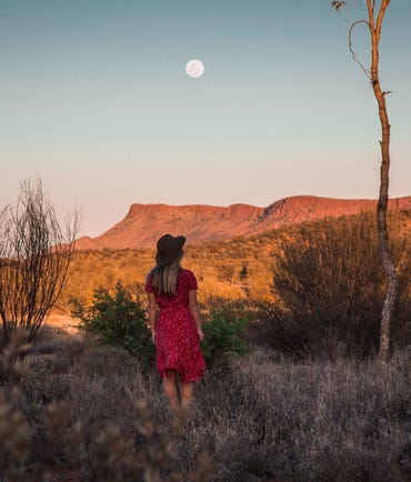 woman taking in scenic view and moon in the west macdonnell ranges
