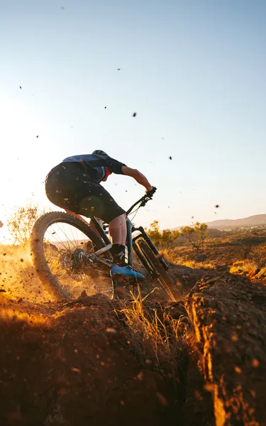 manonamountainbikeridingaggresivelydownhillatsunriseinalicespringswithrangesinthebackgroundjpg