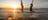 Two girls mid-air jumping out of the water at Casuarina beach