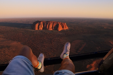 man in helicopter looking at uluru