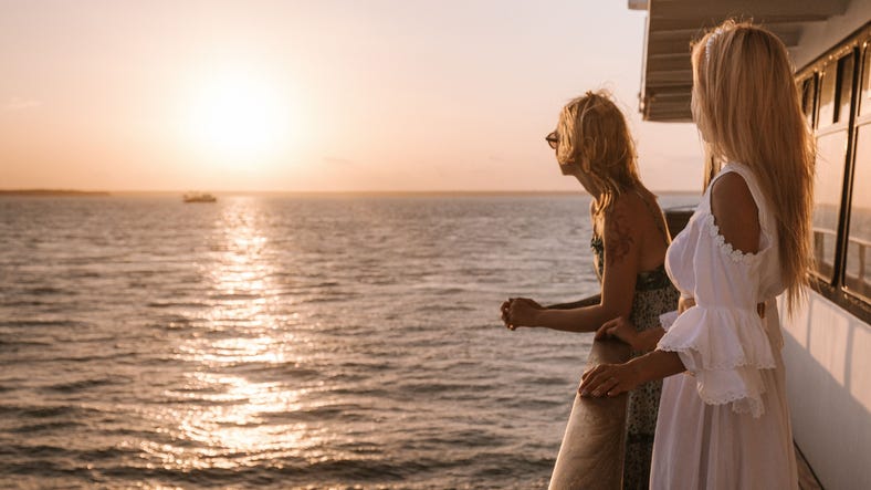 Two women standing at a rail watching the sunset on the Darwin Harbour Cruise tour