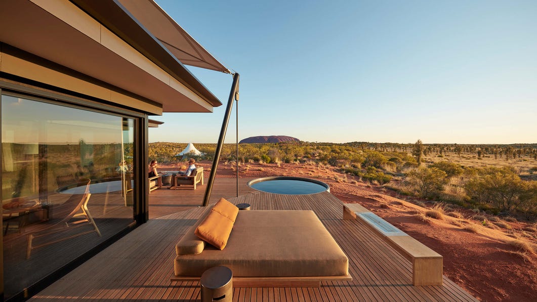 Uluru seen from the deck of the Longitude 131 with a couple conversing on the left
