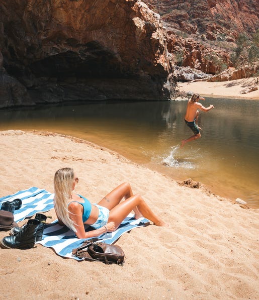 guyjumpingintothewaterholeatormistongorgewhilehisgirlfriendissunbathingonthesandyshorejpg