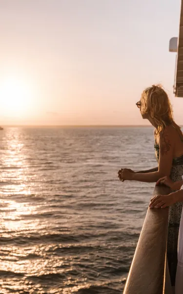 Two women standing at a rail watching the sunset on the Darwin Harbour Cruise tour