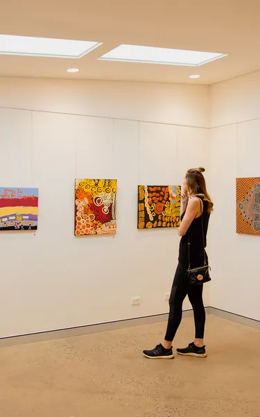 Girl looking at Aboriginal paintings at Tangentyere Artists Aboriginal Art Centre