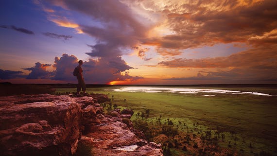 A visitor looks out at sunset at Ubirr lookout in Kakadu