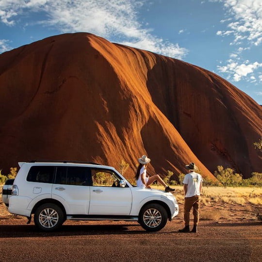 Couple on a red centre road trip stopping in front of Uluru
