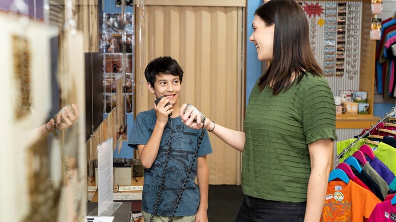 Woman and boy smiling, holding intercoms at School of the Air store