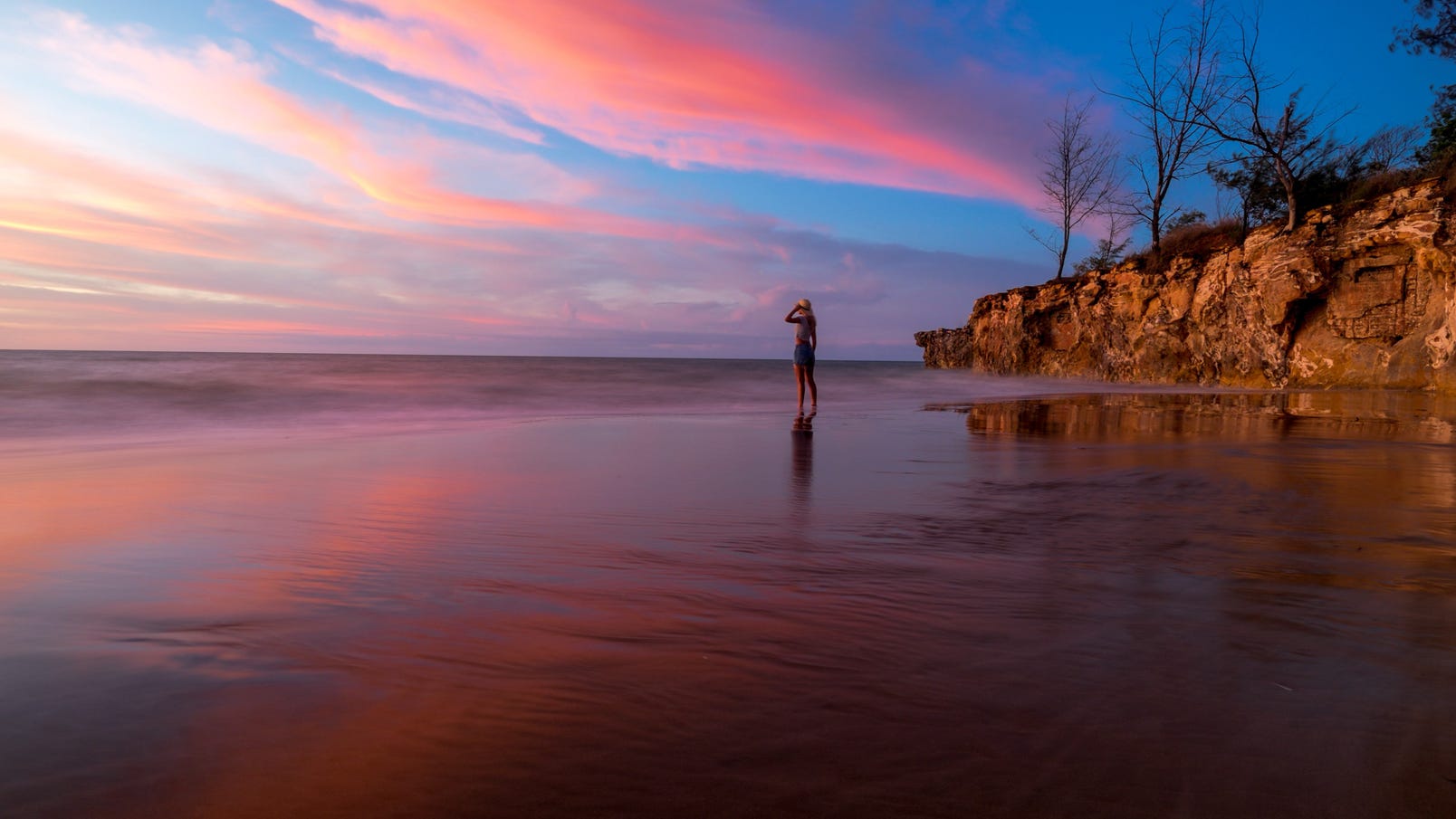 Girl standing on Casuarina Beach at sunset