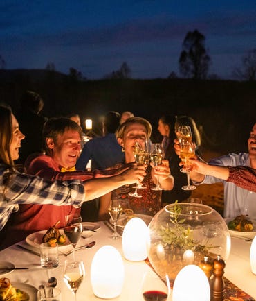 A group of people drinking at a table at night near uluru
