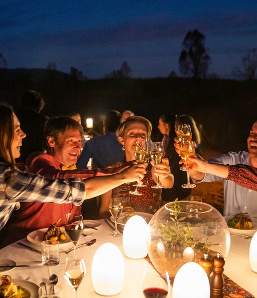 A group of people drinking at a table at night near uluru
