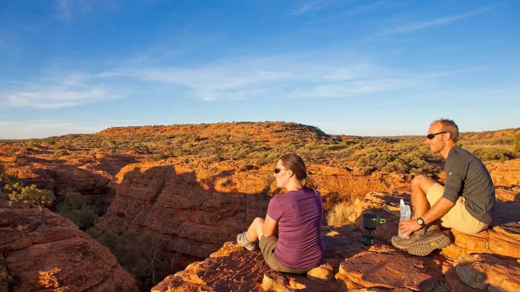 Couple sitting near the edge of kings canyon looking out over the canyon