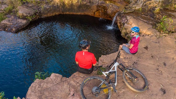 Two people mountain biking near a waterhole in Darwin
