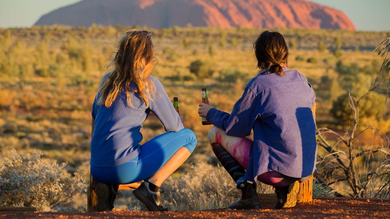 Two people enjoying the view of Uluru at sunset