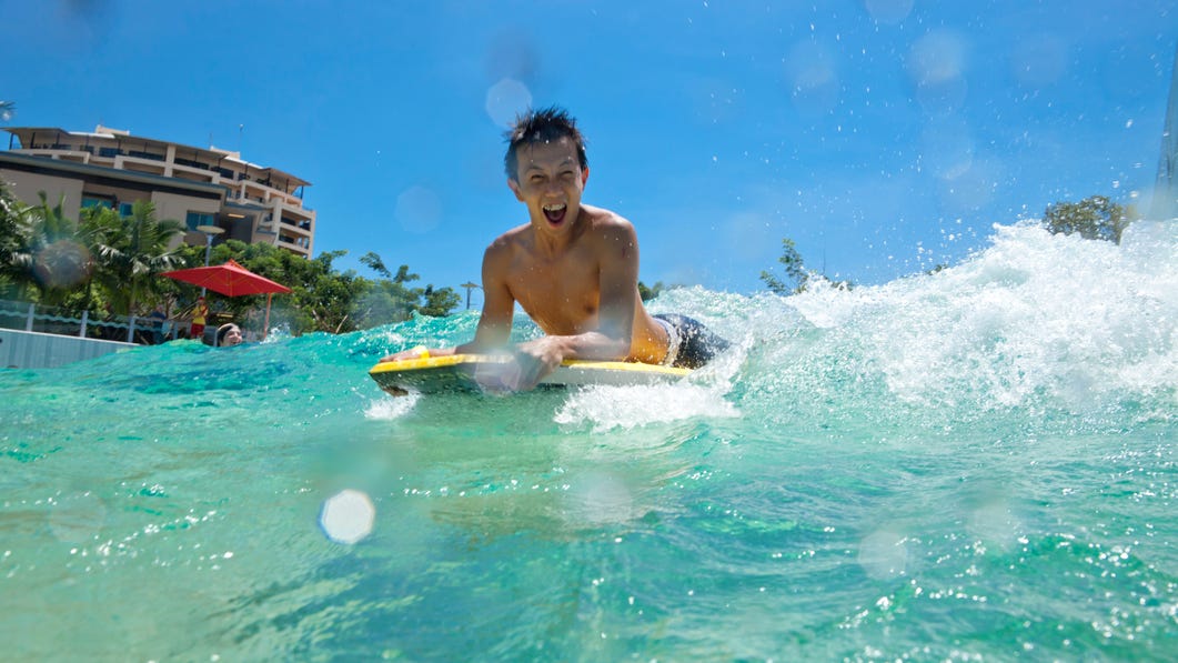 Young visitor riding a wave on a board at the Darwin Wave Lagoon