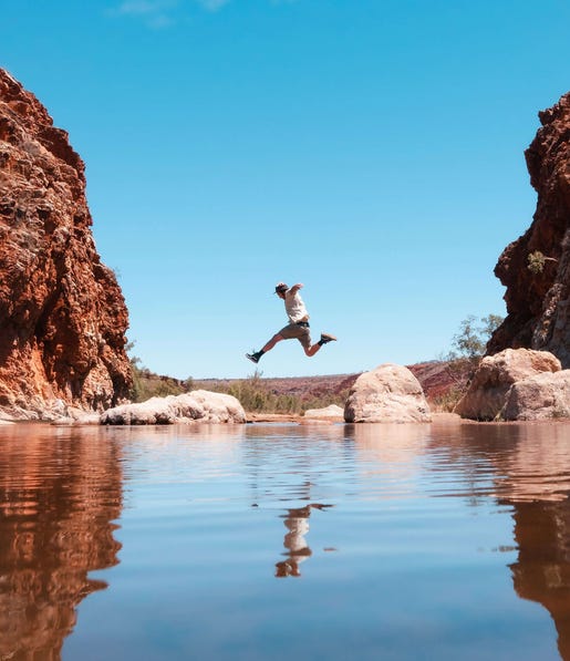 Man jumping over the water at Glen Helen Gorge