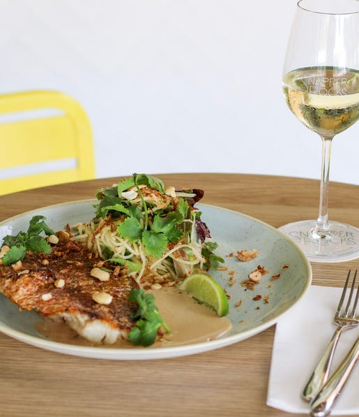 A plated meal at Snapper Rocks with a glass of white wine
