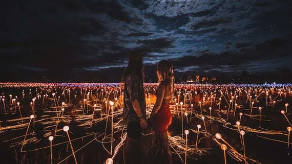 Couple standing in the Field of Light exhibit at Uluru