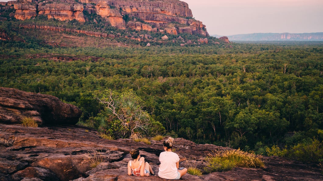Couple sitting on rock looking over at the Burrungkuy (Nourlangie) Rock