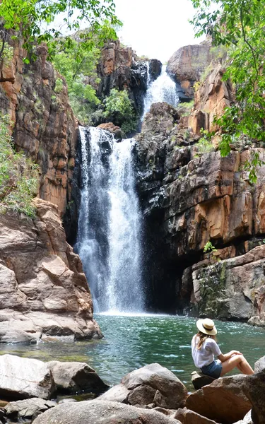 A woman sitting in front of the waterfall at Southern Rockhole near Katherine