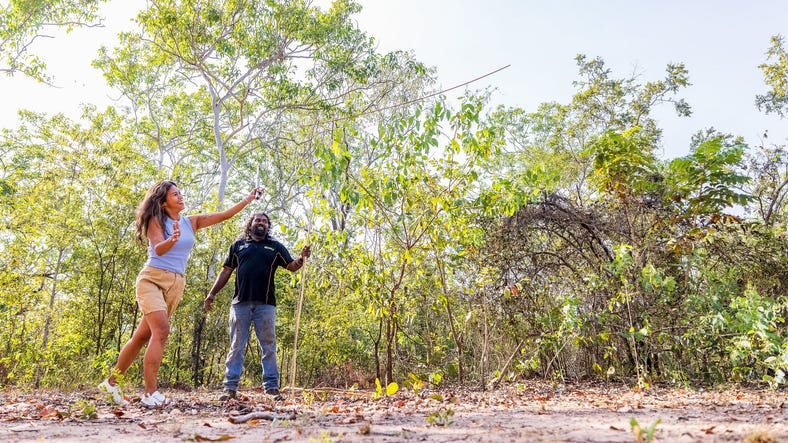 Woman throwing a spear while tour guide watches