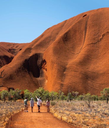 Visitors walking together at the base of Uluru