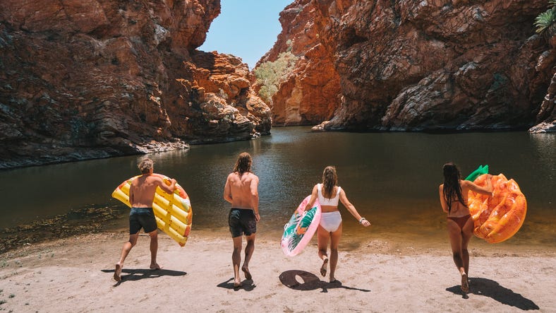 A group of friends running into Ellery Creek Big Hole at West MacDonnell National Park