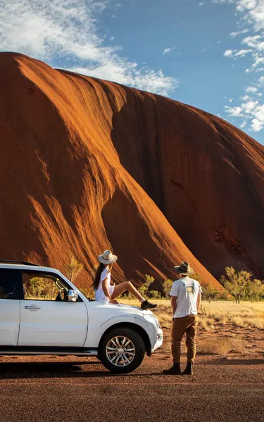 A couple next to their 4WD looking at Uluru