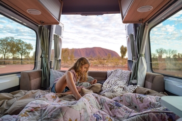 A girl relaxing in her touring van in front of Uluru