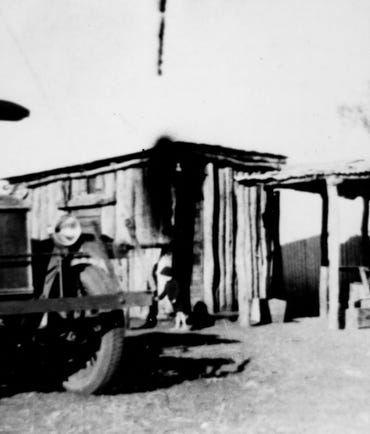 Black and white photo of an old vehicle and an old house